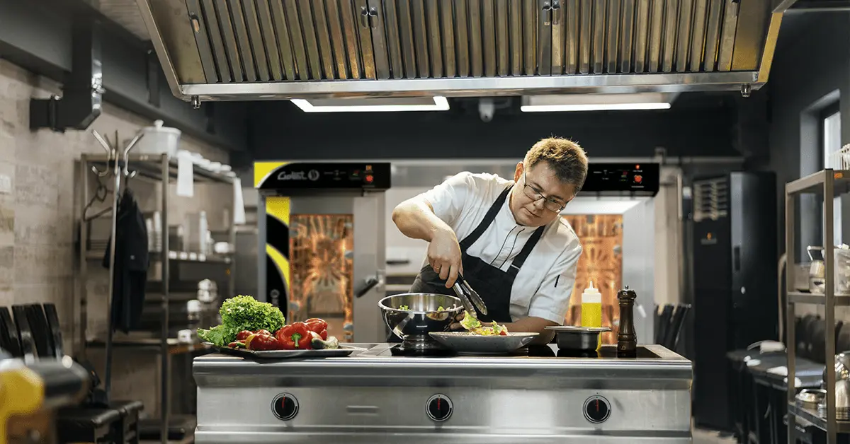 Chef cocinando en una cocina industrial con hornos de convección LINHER al fondo