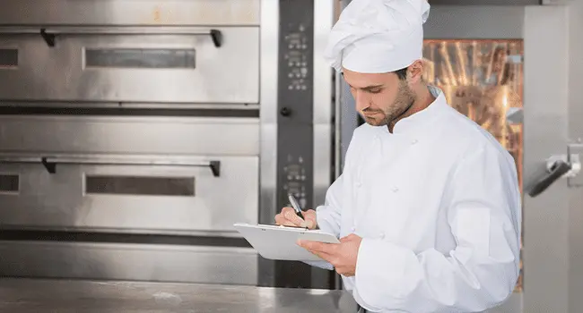 Chef verificando y anotando en unas notas la eficiencia del funcionamiento de su horno de conveccion ideal