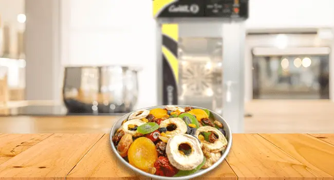 frutos deshidratados con una técnica de cocción en hornos de convección colocados en una mesa con un horno de conveccion en el fondo