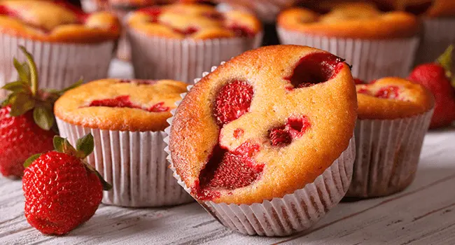 Muffins de frutas, un aperitivo mostrado en conjunto sobre una mesa de cocina fresas alrededor