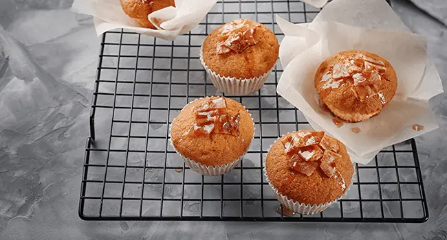 Rejilla de enfriamiento con deliciosos muffins de tocino en la mesa