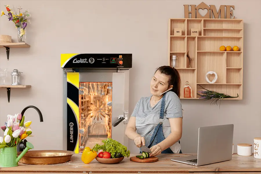 Vista de una mujer cortando vegetales con un horno de convección al fondo