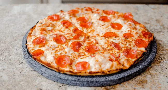 Vista frontal de una pizza de pepperoni sobre una piedra para hornear pizza