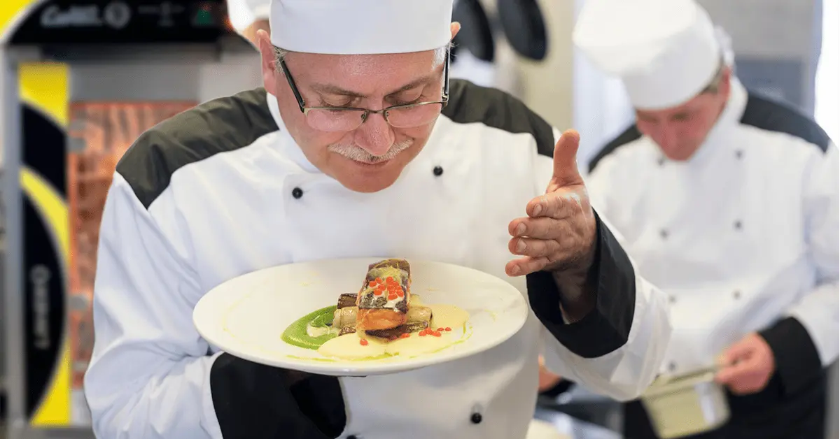 Chef oliendo platillo después de ser cocinado con un horno de convección LINHER al fondo