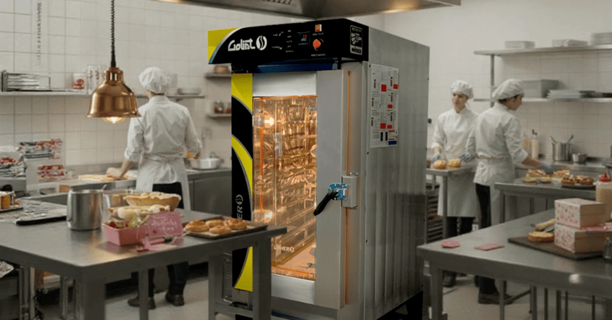 Cocina profesional con horno de convección industrial y producción activa para el Día de las Madres, con empaques festivos y personal trabajando con orden.